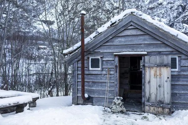 Eit par skistavar og ein sekk utanfor ein open dør til Bjørn West stølen i Matre