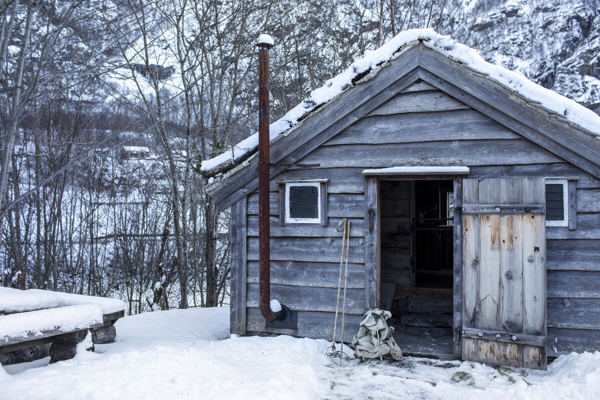 Eit par skistavar og ein sekk utanfor ein open dør til Bjørn West stølen i Matre