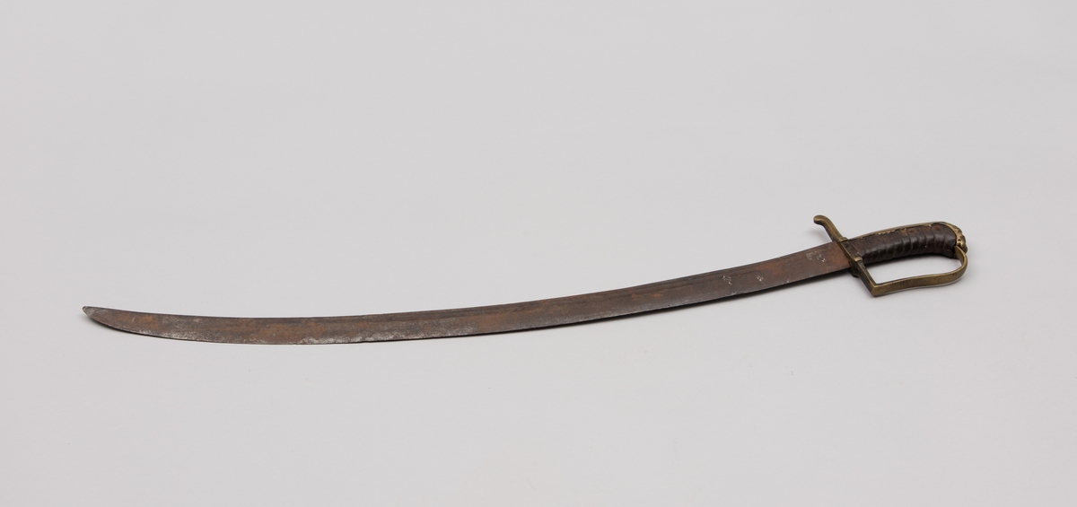 Sabelen er litt krum. Avviket frå rett line gjennom skjefte- aksen er 14.5 cm på 78 cm (mælt frå toppen av skjeftet).Skjeftet har parerstong av messing,ein volutt på den rette toppenden. Under går parerstonga vinkelrett over i ein litt boga vernebøyle opp mot skjeftetoppen av messing, forma som anletsmaske. Grepet er av lær. Klingen av stål har smal blodrand og har utvendig egg.