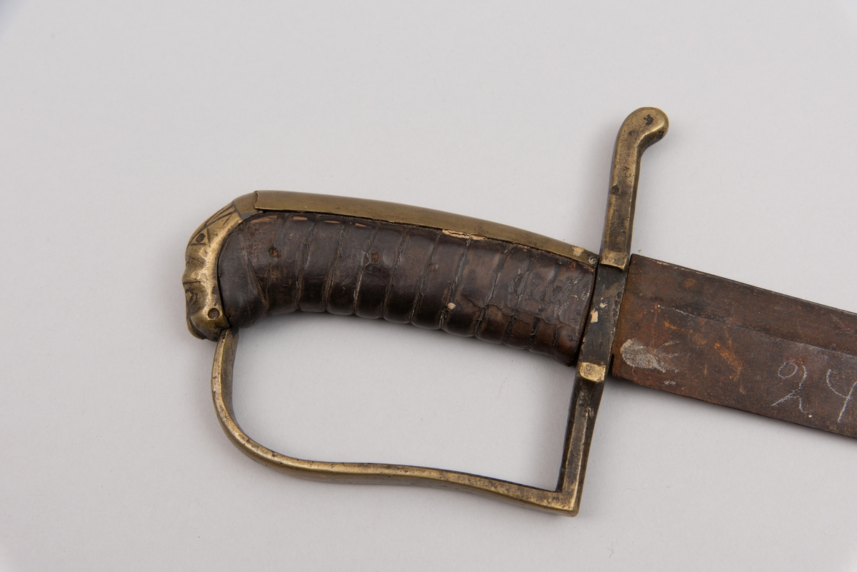 Sabelen er litt krum. Avviket frå rett line gjennom skjefte- aksen er 14.5 cm på 78 cm (mælt frå toppen av skjeftet).Skjeftet har parerstong av messing,ein volutt på den rette toppenden. Under går parerstonga vinkelrett over i ein litt boga vernebøyle opp mot skjeftetoppen av messing, forma som anletsmaske. Grepet er av lær. Klingen av stål har smal blodrand og har utvendig egg.