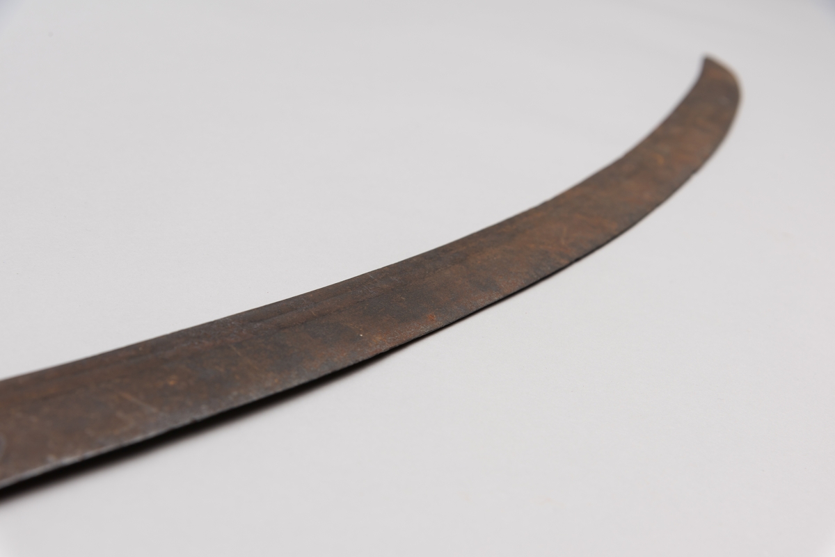 Sabelen er litt krum. Avviket frå rett line gjennom skjefte- aksen er 14.5 cm på 78 cm (mælt frå toppen av skjeftet).Skjeftet har parerstong av messing,ein volutt på den rette toppenden. Under går parerstonga vinkelrett over i ein litt boga vernebøyle opp mot skjeftetoppen av messing, forma som anletsmaske. Grepet er av lær. Klingen av stål har smal blodrand og har utvendig egg.
