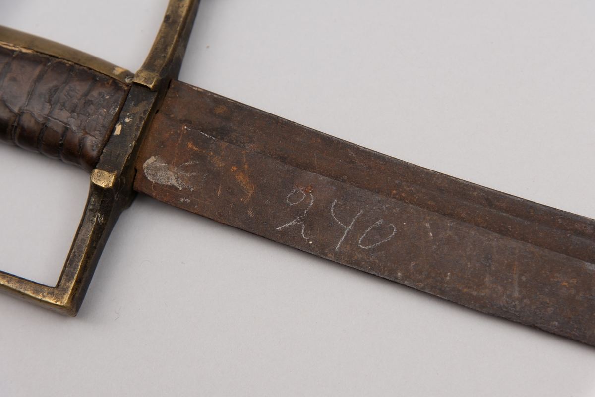 Sabelen er litt krum. Avviket frå rett line gjennom skjefte- aksen er 14.5 cm på 78 cm (mælt frå toppen av skjeftet).Skjeftet har parerstong av messing,ein volutt på den rette toppenden. Under går parerstonga vinkelrett over i ein litt boga vernebøyle opp mot skjeftetoppen av messing, forma som anletsmaske. Grepet er av lær. Klingen av stål har smal blodrand og har utvendig egg.