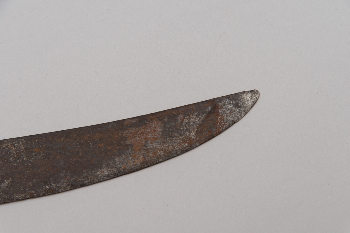 Sabelen er litt krum. Avviket frå rett line gjennom skjefte- aksen er 14.5 cm på 78 cm (mælt frå toppen av skjeftet).Skjeftet har parerstong av messing,ein volutt på den rette toppenden. Under går parerstonga vinkelrett over i ein litt boga vernebøyle opp mot skjeftetoppen av messing, forma som anletsmaske. Grepet er av lær. Klingen av stål har smal blodrand og har utvendig egg.