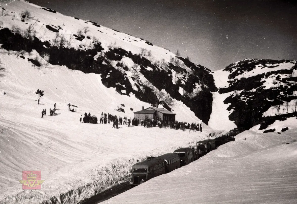 Stor utfart til skisøndag på Ramsdalsheia på grensa mellom Flora og Naustdal kommune omlag år 1950. Gamle bussar er parkert langs vegen og mykje folk er samla ved Trollstova.