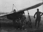 Närbild av flygplan Thulin A som havererat vid landning, 1910-talet. En man står bredvid flygplanet. Oskarp bild.