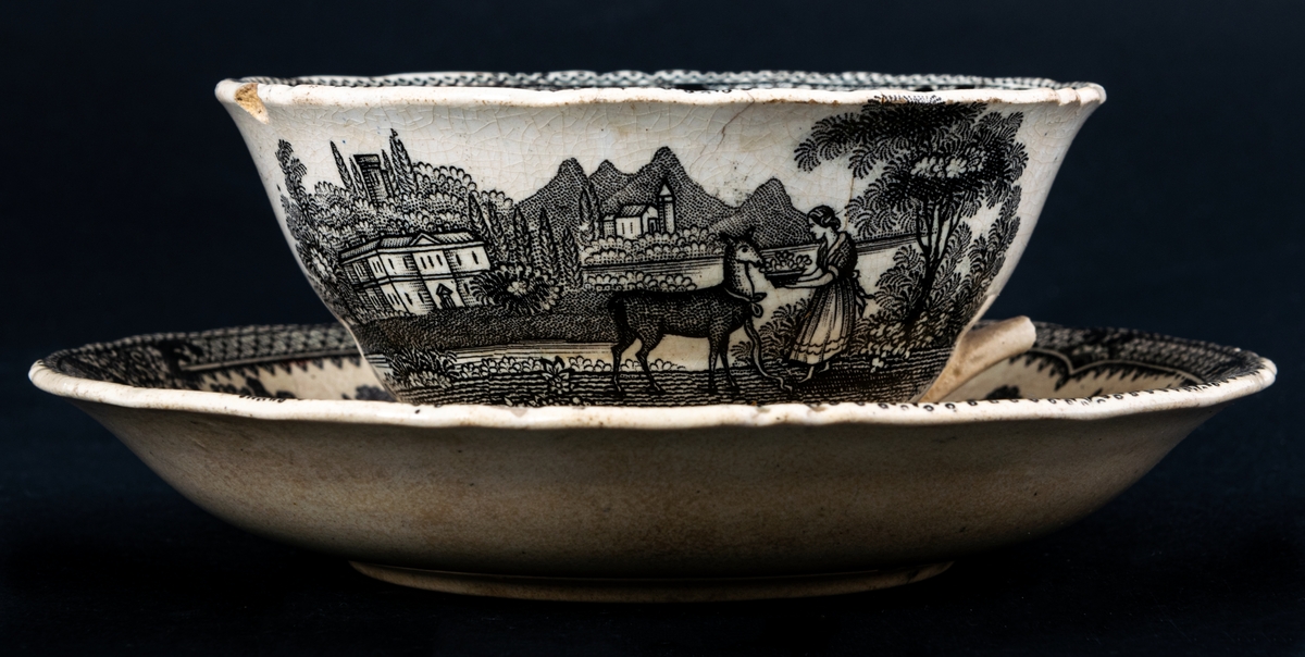 Kaffekopp och fat, med svartvit dekor med landskapsmotiv och blommor. Tillverkad vid Gustavsbergs porslinsfabrik.