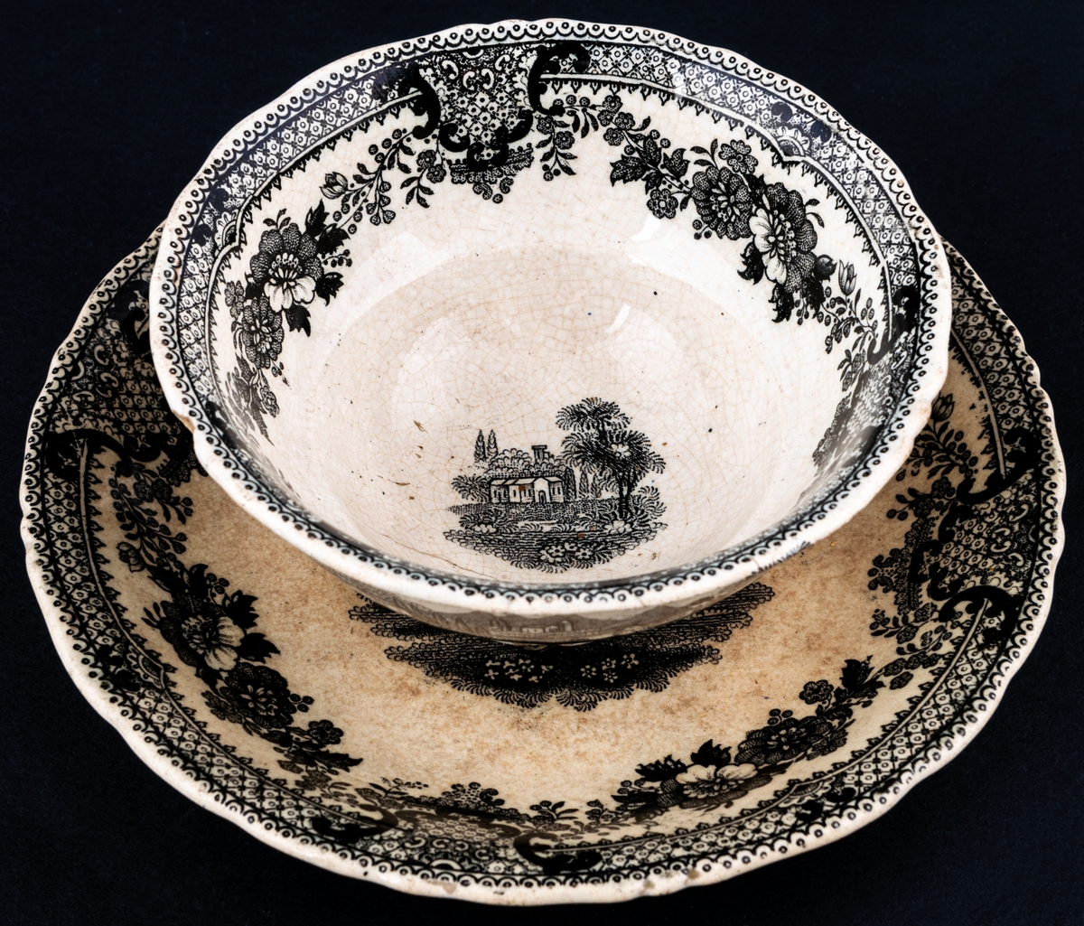 Kaffekopp och fat, med svartvit dekor med landskapsmotiv och blommor. Tillverkad vid Gustavsbergs porslinsfabrik.