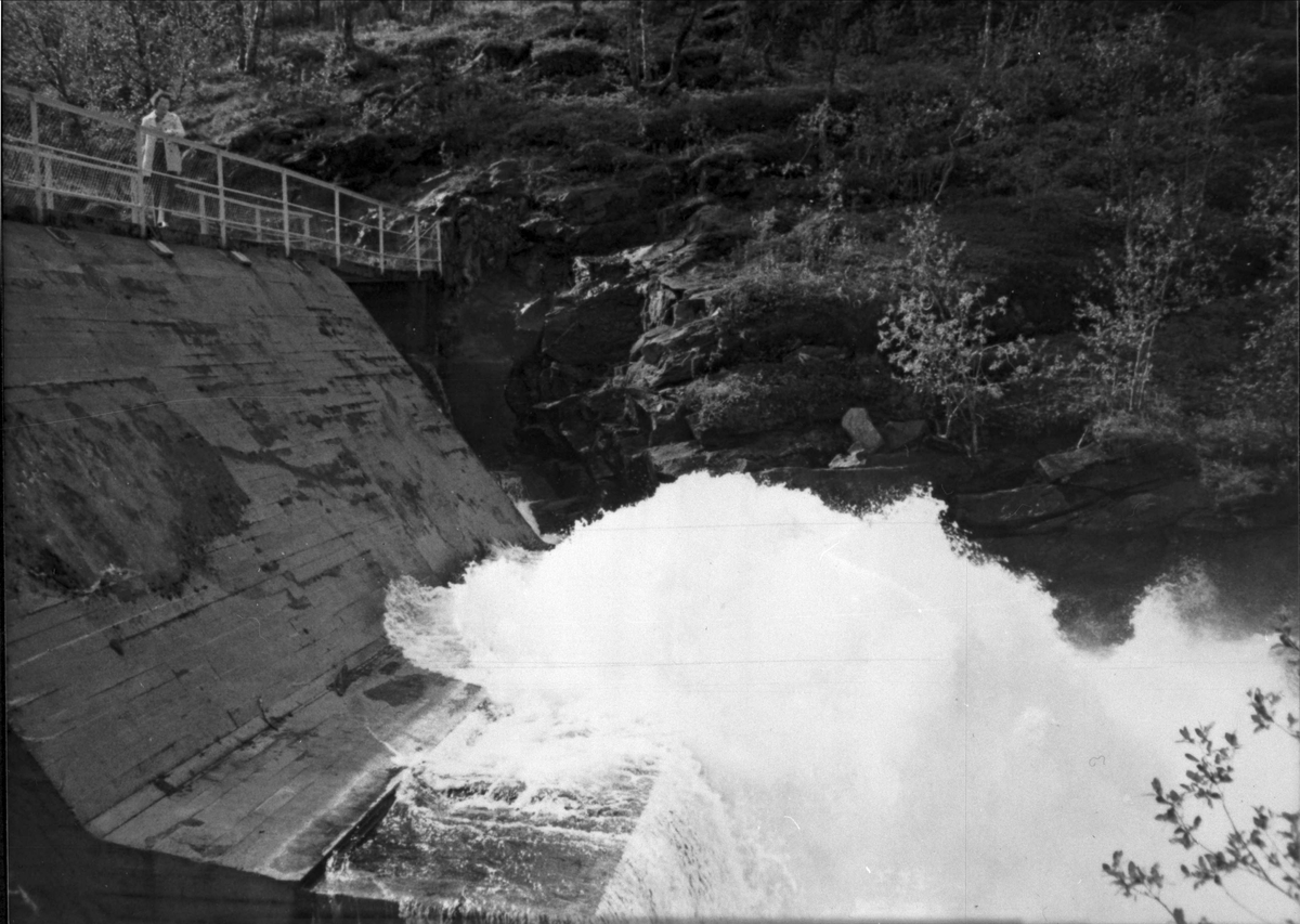 Demningen ved Skoddebergvann. En kvinne står ved rekkverket oppå.