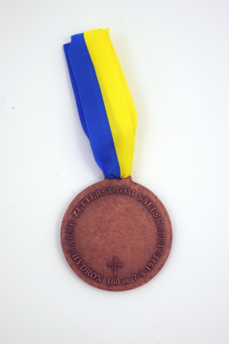 Minnesmedalj av koppar. Framsidan präglad av relief av tungdykarhjälm med Zetterströmventil samt krans av murgröna. Baksidan har text präglad: "Arne Zetterström sällskapet. Hydrox 160 m 7.8 1945" samr yta i mitten för gravering. Ögla i medaljens överkant där blå-gult ripsband är fäst.