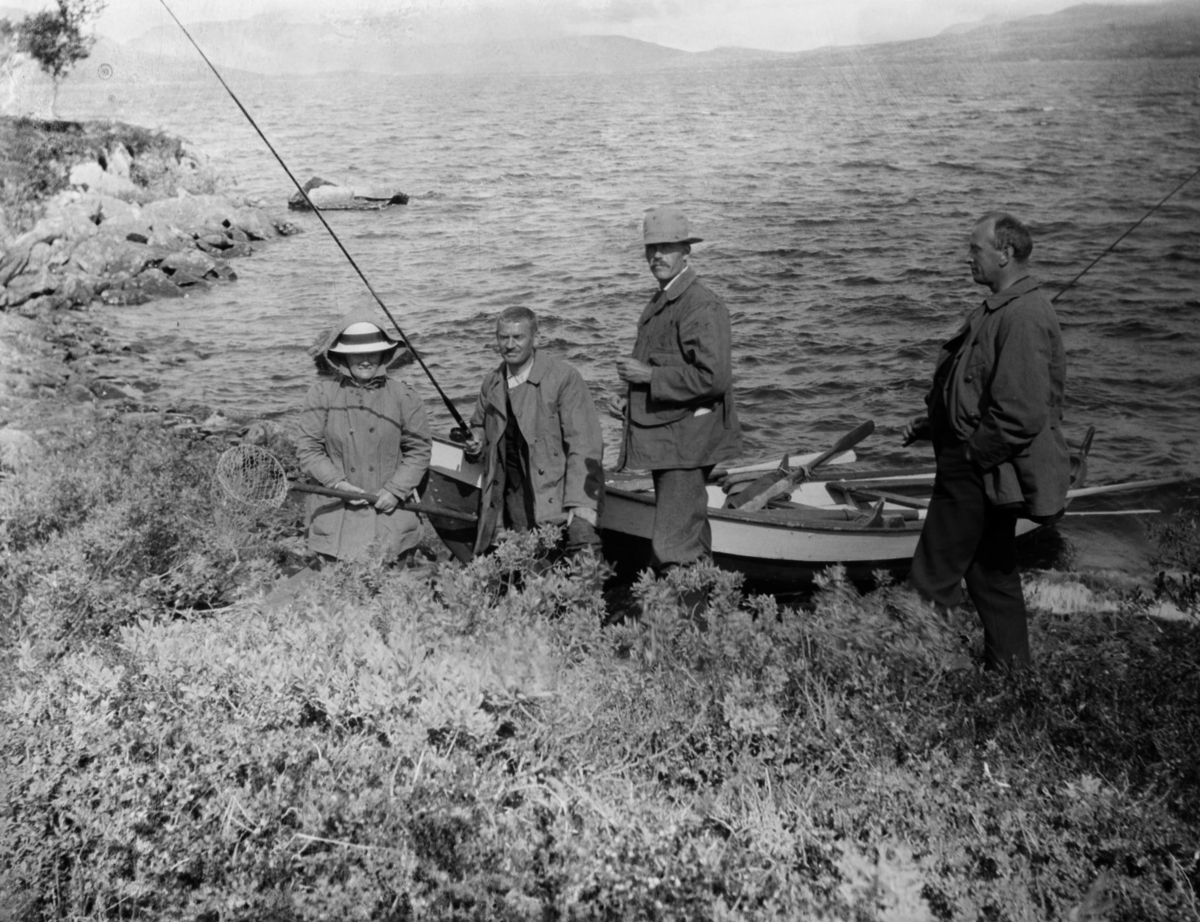 Tre menn og en dame, fiskere ved et fjellvann. Fiskestenger og et fiskenett, Stedet er antageligvis Aursjøen