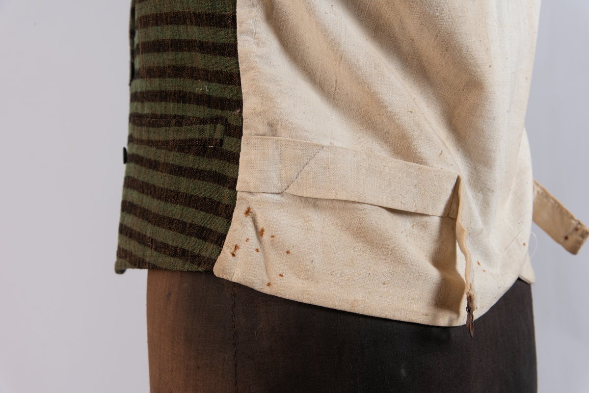 Dobbeltspent vest i ullverken, stripet i grønt og svart (sauesvart) med brun renning. Dobbel rygg i bomullslerret. Halvlinslerret (bomull/stry) i fôret i framstykkene. Vesten har fire knapphull sydd med kamgarnsullgarn og svarte knapper trukket med svart bomullssateng med brun renning. Plagget har nedbrettet krage og slag/reverser som kan kneppes mot bolen. Knapp og knapphull. Vesten buer ned midt framme og har svakt skråstilte lommer. Vattering av stry i framstykkene. I ryggen buer vesten opp midt bak. Den er vrangsydd langs ytterkantene og stukket ned med maskin, 0,8 cm fra kanten. (Registrering ved Bunad- og folkedraktrådet/Norsk institutt for bunad og folkedrakt v/Jon Fredrik Skauge, 2005, revidert v/Bjørn Sverre Hol Haugen, 2020.)