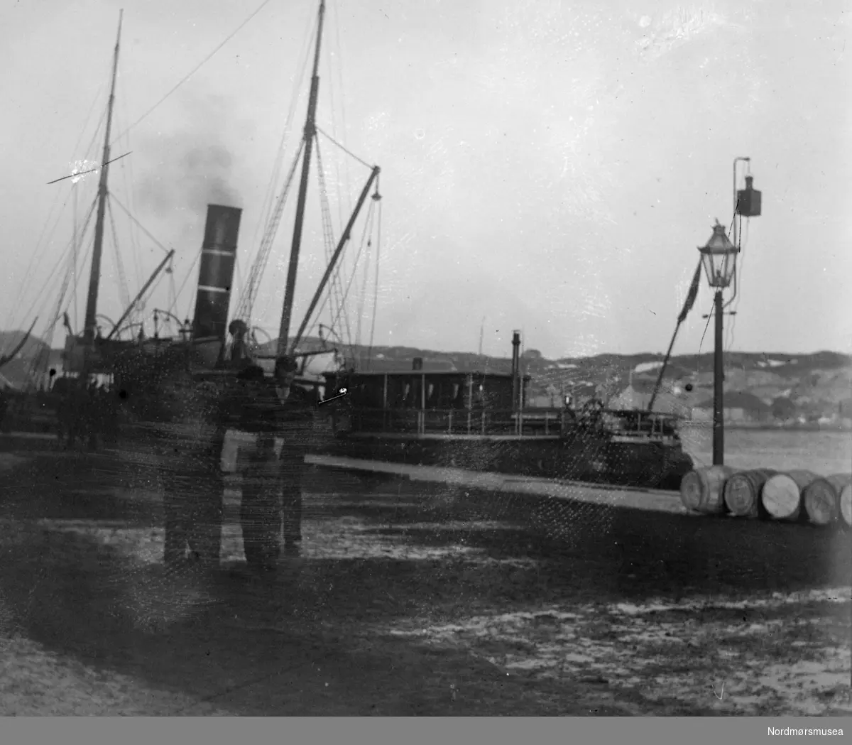 En rutebåt ved kai, muligens i Kristiansund. Utydelig fotografi. Fra en fotosamling etter Bernhard Torske, gitt av enken Mary Torske til Tor Helge Gravem, som vinteren 2021 gav samlingen videre til Nordmøre museum. Samlingen består av 37 glassnegativer. Fotograf er trolig Ole Ranheimsæter som omkring 1916 flyttet til Sunndalsøra. Fra Nordmøre museums fotosamlinger.