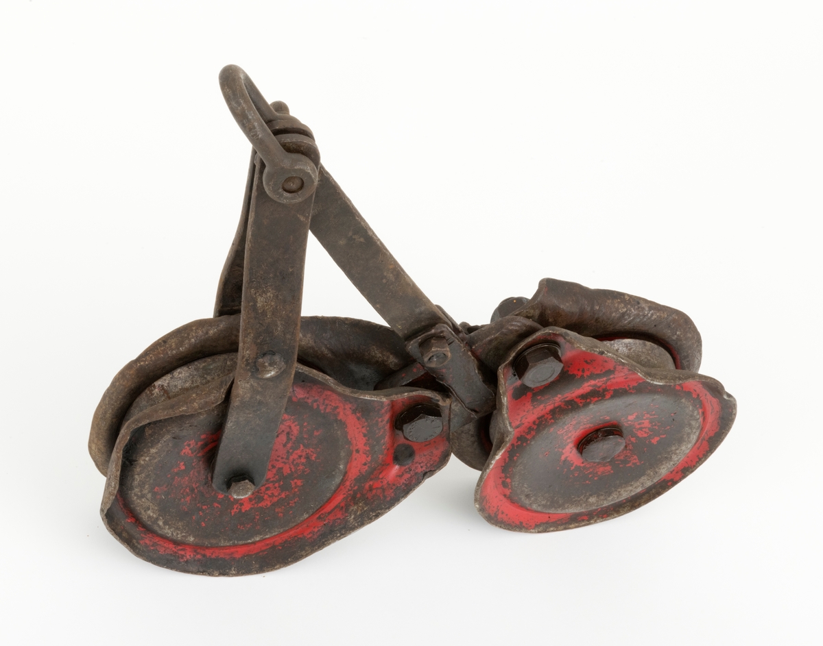 Løpekatt for slepebane som består av to kraftige blokker med oppheng i et mellomstykke konstruert av flattjern. Hver blokk består av en roterende skive, to sideplater (en på hver side av skiven) og en gjennomgående festebolt i midten. Blokkens skive har et spor der ståltauet, som lasten henges i, legges. Øverst på blokkene er det gjennombrutt hull i sideplatene. Blokkene er festet til mellomstykket med bolter som er tredd gjennnom hullene i sideplatene. På toppen av opphenget er det festet en sjakkel. Løpekatten er preget av bruk og er preget av en del ytre påkjenninger. En slik løpekatt kunne f. eks. brukes med traktormontert stammelunningsvisnj som var tilleggsutstyrt for stammelunning med slepebane.   
(Løpekattens bruk sammen traktormontert vinsj, se vedlagt fil under fanen "Referanser til filer")

Løpekatten er brukt som hjelpeutstyr i forbindelse med transport av tømmer med vinsj i bratt og ulendt terreng. I løpekatten festes lasset for transport. Løpekatten henger på kabelkranas bærekabel. Løpekatten fører tømmeret langs bærekabelen enten oppover eller nedover dalsiden.