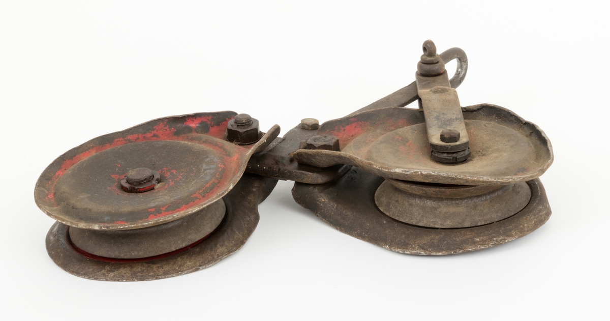 Løpekatt for slepebane som består av to kraftige blokker med oppheng i et mellomstykke konstruert av flattjern. Hver blokk består av en roterende skive, to sideplater (en på hver side av skiven) og en gjennomgående festebolt i midten. Blokkens skive har et spor der ståltauet, som lasten henges i, legges. Øverst på blokkene er det gjennombrutt hull i sideplatene. Blokkene er festet til mellomstykket med bolter som er tredd gjennnom hullene i sideplatene. På toppen av opphenget er det festet en sjakkel. Løpekatten er preget av bruk og er preget av en del ytre påkjenninger. En slik løpekatt kunne f. eks. brukes med traktormontert stammelunningsvisnj som var tilleggsutstyrt for stammelunning med slepebane.   
(Løpekattens bruk sammen traktormontert vinsj, se vedlagt fil under fanen "Referanser til filer")

Løpekatten er brukt som hjelpeutstyr i forbindelse med transport av tømmer med vinsj i bratt og ulendt terreng. I løpekatten festes lasset for transport. Løpekatten henger på kabelkranas bærekabel. Løpekatten fører tømmeret langs bærekabelen enten oppover eller nedover dalsiden.