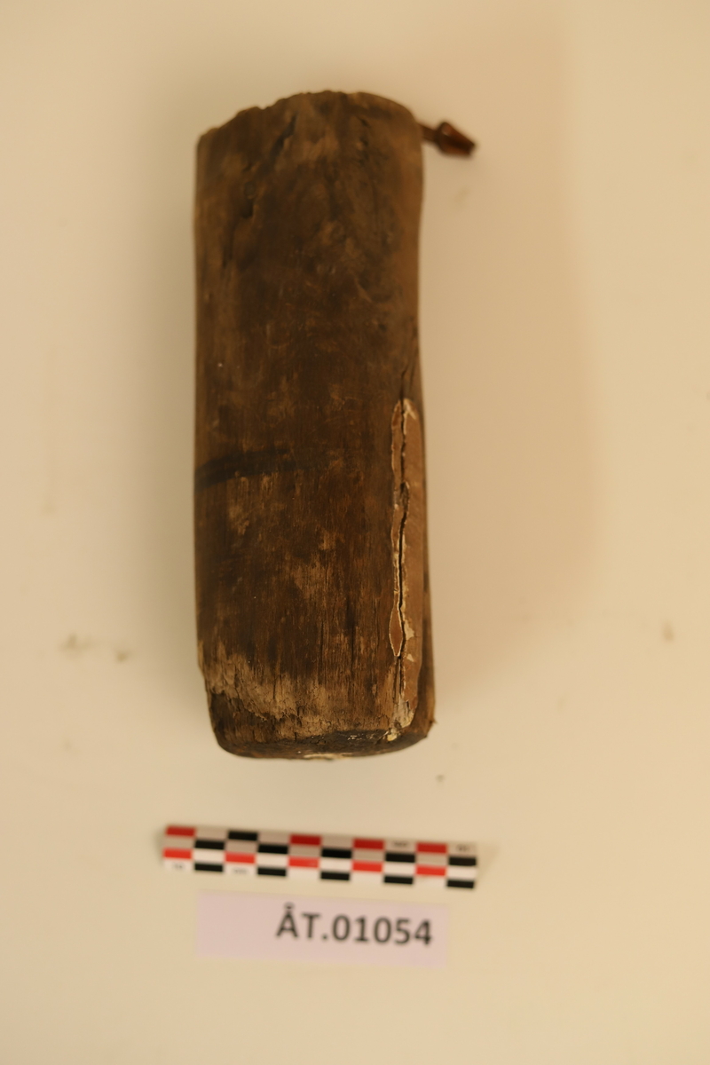 Trekopp til å ha bryne i. Koppen er hulet ut av et stykke tre med en metallkrok i toppen. Rundt koppen er det to sorte striper som er malt på. Under metallkroken er det en reparasjon med noe hvitt. Inni er en brynesten som er tynnere i tuppen og hull i enden. Stenen er lysegrå. Koppen bærer preg av sprekker og oppleves som litt skjør. 