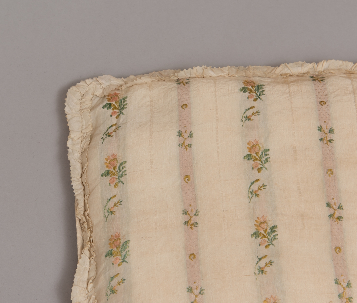 Dåpsløyert med pute samt løse ermer og en blondekrage. Løyerten er sydd av et ecrufarget silkestoff med stripemønster hvor det er innvevd blomster og blader. Løyerten lukkes med to sett knyteband, det ene settet er enkle bendelband som også snøres gjennom løpeganger, mens det andre er silkeband sydd av stoffet. Langs nederkant har løyerten en rynket kant av hovedstoffet samt et rynket dekorband av ensfarget, ecrufarget silke. Løyerten er fôret med linlerret. Ermene er sydd av hovedstoffet og har dekor av samme rynkede silkeband, men er uten fôr. Trolig har ermene vært tråklet til ei undertrøye som dåpsbarnet har hatt under reiven. Kragen, som er av tyllblonde, trolig i lin med silketråder og silkeband, er vid, så den har trolig vært rynket med ei snor og tråklet til undertrøya. Da barnet lå som en reivet bylt inne i løyerten, var det bare ermene som kom til syne, derfor var det ikke nødvendig med ei hel trøye. Alternativt kan det være at ermene tidligere har sittet på ei silketrøye som nå er fjernet.