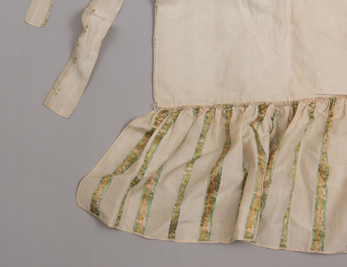 Dåpsløyert med pute samt løse ermer og en blondekrage. Løyerten er sydd av et ecrufarget silkestoff med stripemønster hvor det er innvevd blomster og blader. Løyerten lukkes med to sett knyteband, det ene settet er enkle bendelband som også snøres gjennom løpeganger, mens det andre er silkeband sydd av stoffet. Langs nederkant har løyerten en rynket kant av hovedstoffet samt et rynket dekorband av ensfarget, ecrufarget silke. Løyerten er fôret med linlerret. Ermene er sydd av hovedstoffet og har dekor av samme rynkede silkeband, men er uten fôr. Trolig har ermene vært tråklet til ei undertrøye som dåpsbarnet har hatt under reiven. Kragen, som er av tyllblonde, trolig i lin med silketråder og silkeband, er vid, så den har trolig vært rynket med ei snor og tråklet til undertrøya. Da barnet lå som en reivet bylt inne i løyerten, var det bare ermene som kom til syne, derfor var det ikke nødvendig med ei hel trøye. Alternativt kan det være at ermene tidligere har sittet på ei silketrøye som nå er fjernet.