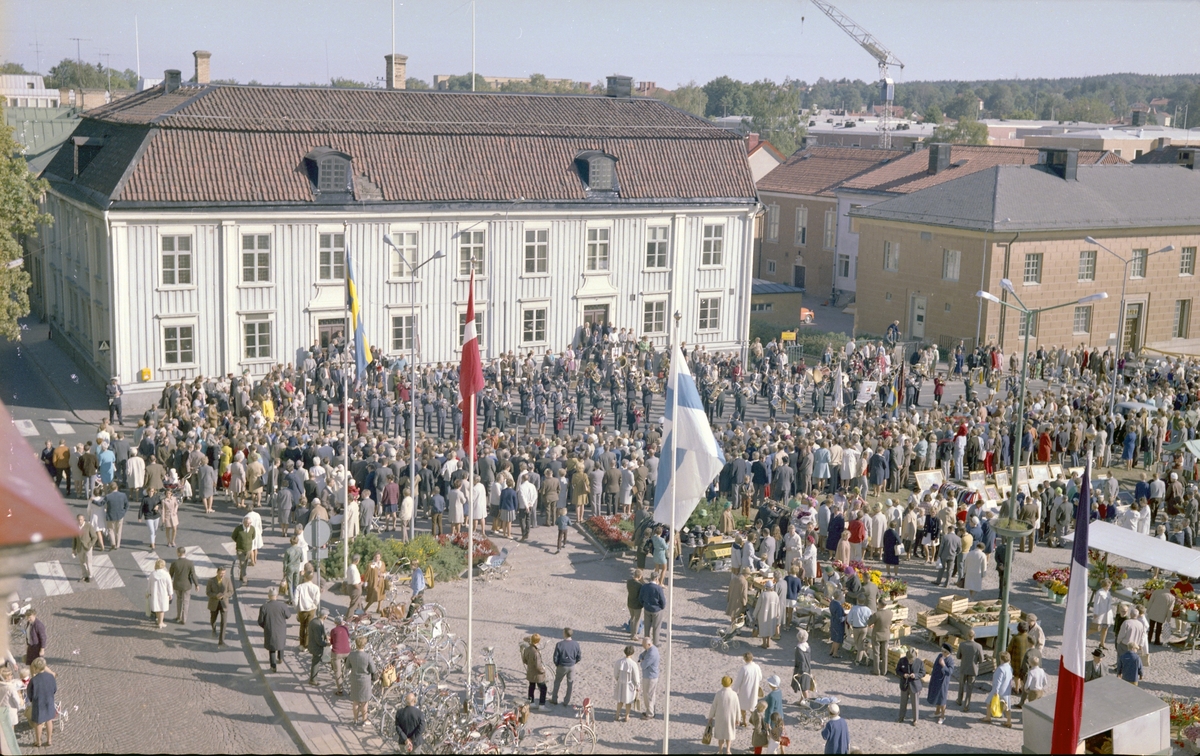 OBS SPEGELVÄND

Musikkår uppställd framför rådhuset i kv Kristina, samtidigt pågår sedvanlig torghandel på Stora torget. Folksamling.

Utländska flaggor, bland annat den finska.