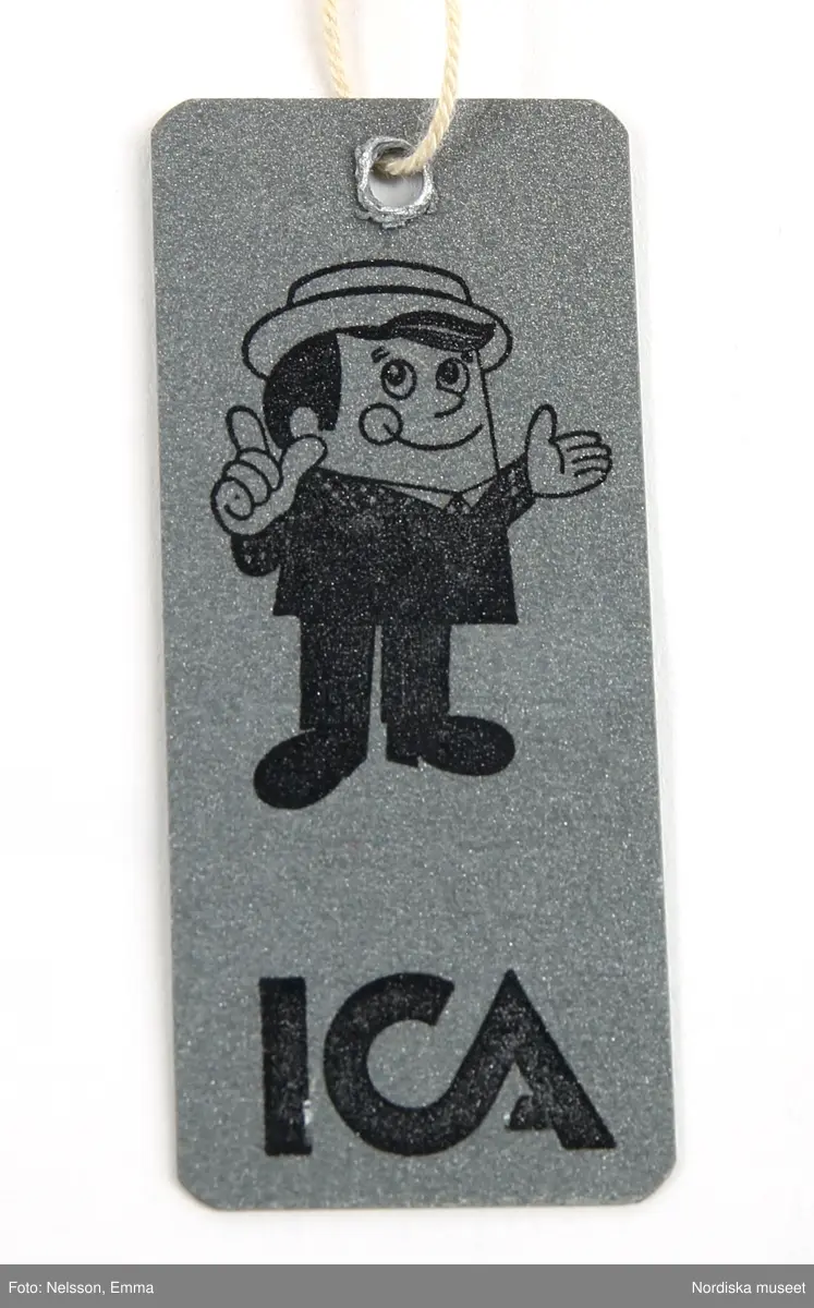 Katalogkort:
"Overall f. pojke av mörkblå s.k. "bäver-nylon" kypertvävnad av 50% polyamid och 50% bomull (mycket slitstark används till arbetskläder och barnkläder) fodrad med röd acrylpile i överdelen och med syntetvadd rutstickad med röd nylon i benen och ärmarna. 
Helskuren modell med besparing på axlarna fram, resår i midjan bak, isydd lång ärm med röda muddar av acryltrikå, lång rött blixtlås fram ned till grenen, rak krage med rött pilefoder, 2 påsydda framfickor med rött pilefoder och knäppta med slejf och nitad tryckknapp. Förstärkt med extra tyg på knäna. Fastsydd vitmetallhake på bröstet att fästa skidhandskarna i. Märke i vitt: Tuffis Reflexbricka i snöre fäst bak på kragen med säkerhetsnål."