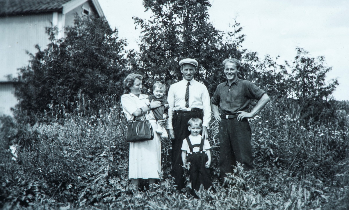 Familie gruppe. Fra venstre ser vi Karen Agnethe Flagstad med Karin Flagstad på armen. Ved siden av står Ole Flagstad, Gunnar Godager og lille Arne Flagstad. Bildet er tatt på Flagstad. Til venstre i bildet står stabburet, som i 1967 ble flyttet, mellom steinfjøset og låven.