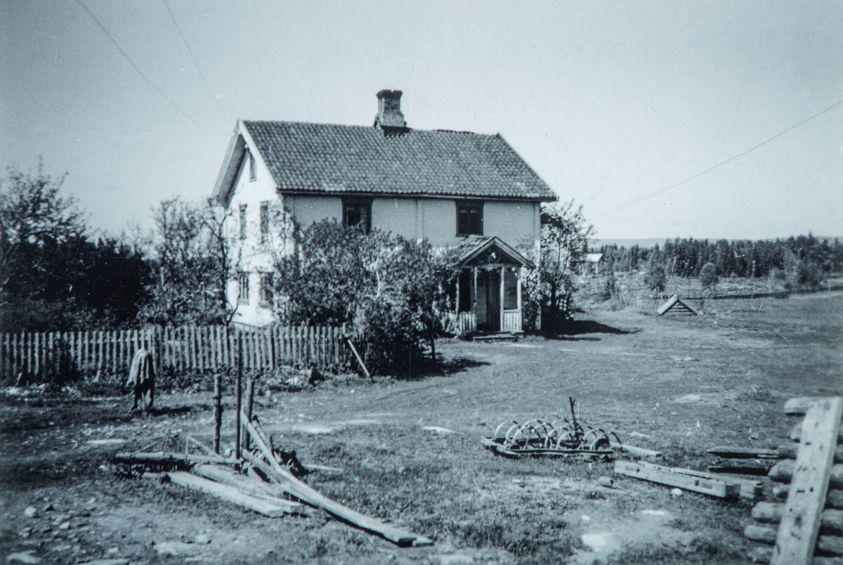 Flagstad Gård. Hovedhuset på Flagstad. Bildet er tatt mot slutten av 30-tallet. Hovedhuset ble bygd i 1874, og er bygd i tømmer. Til høyre for hovedhuset ligger brønnen, under brønnhuset. Hagen ligger til venstre for huset. Rundt på tunet ligger diverse redskaper som: Harv, slådd, og diverse redskap for å få sortert jorda vekk fra potetene før de ble tømt ned i kjelleren.