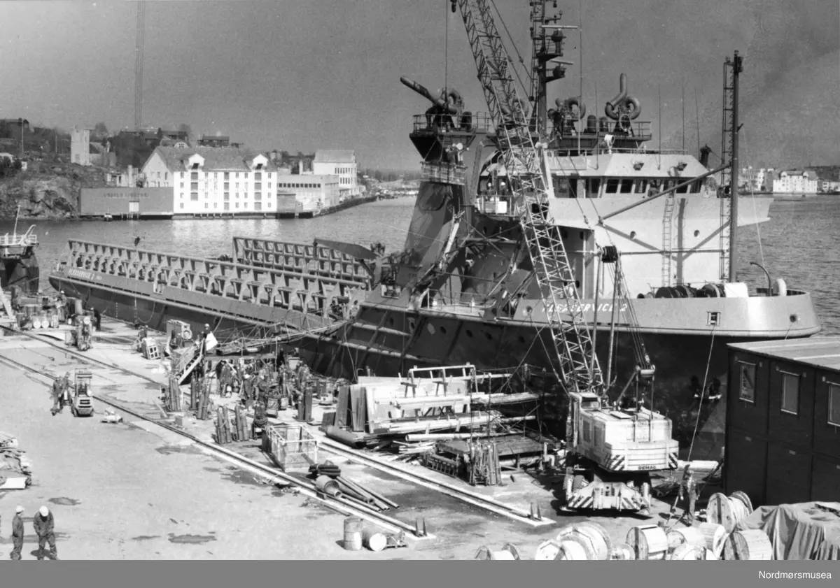 Backerbrygga på Goma. Bygd av Werring Hermanos 1910-1920. Lengde 29m, bredde 19 m, 4 1/2 etasje. klippfiskbrygge brukt til byggvarelager. Strandgata 74, Brant ca år 2000. Bildet er fra avisa Tidens Krav sitt arkiv i tidsrommet 1970-1994. Nå i Nordmøre museums fotosamling.