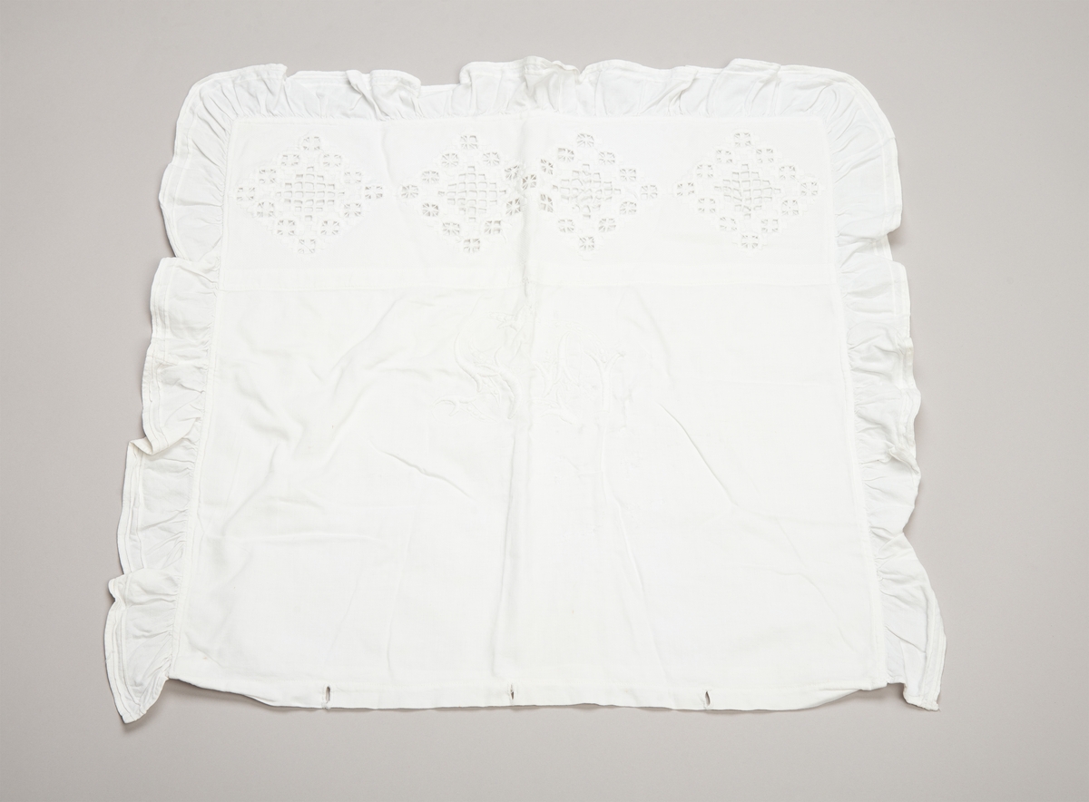 Kvadratisk putevar med rysjekant. Innfelt rektangulært felt med hardangersøm i øvre del. Broderte initialer på midten. Lukning i bunnen med håndlagde trådknapper.