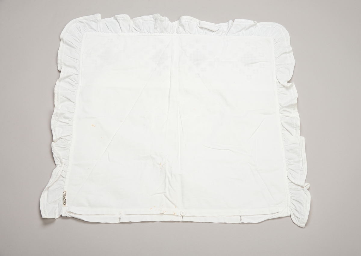 Kvadratisk putevar med rysjekant. Innfelt rektangulært felt med hardangersøm i øvre del. Broderte initialer på midten. Lukning i bunnen med håndlagde trådknapper.