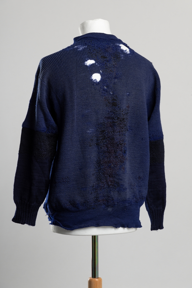 Ullgenser med glidelås i halsen. Genseren er stoppet på hele magen, langs hele midten av ryggen, ved albuene og langs vrangbordene. Ermene er byttet ut med nye fra albuen.