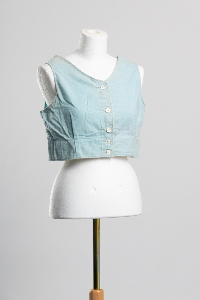 Hjemmelaget formsydd underliv av turkis bomullsflanell uten ermer. Åpning i front med knappelukkning, fem perlemorsknapper.