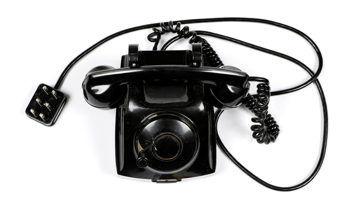 Svart telefonapparat i plast med sveiv, men uten tallskive.
Telefoner uten tallskive var tilknyttet manuelle telefonsentraler, og en brukte sveiva for å kommer i kontakt med sentralen, hvor det falt en klaff over linjejakken, et hvitt flagg og på større sentraler et lys over linjejakken. 
Denne het Elektrisk Burerau 1953 modell og ble produsert til 1967 i et antall 153 400 eksemplarer