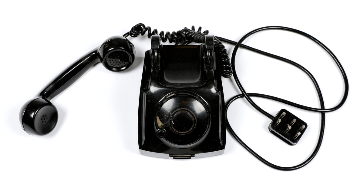 Svart telefonapparat i plast med sveiv, men uten tallskive.
Telefoner uten tallskive var tilknyttet manuelle telefonsentraler, og en brukte sveiva for å kommer i kontakt med sentralen, hvor det falt en klaff over linjejakken, et hvitt flagg og på større sentraler et lys over linjejakken. 
Denne het Elektrisk Burerau 1953 modell og ble produsert til 1967 i et antall 153 400 eksemplarer