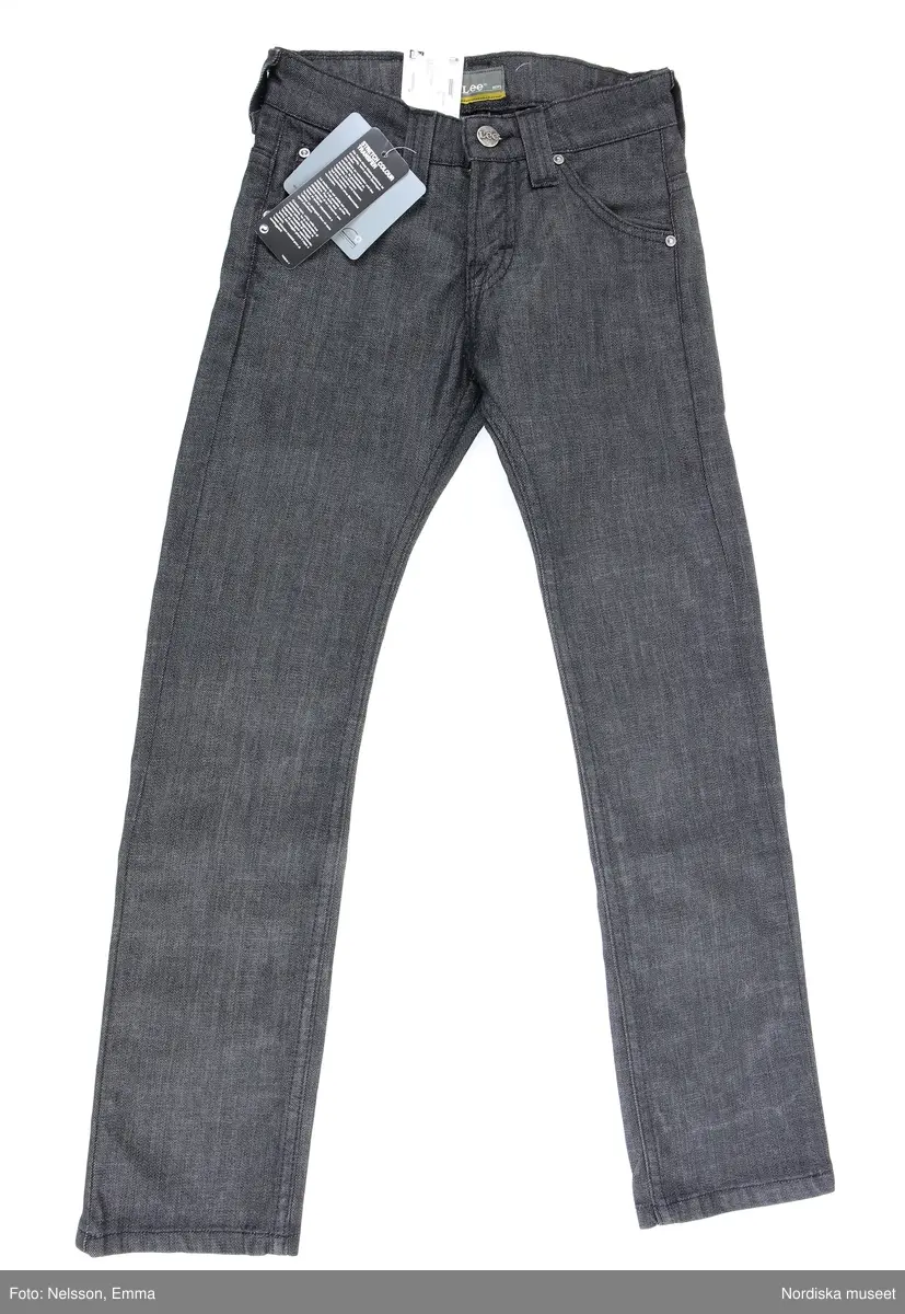 Långbyxor - jeans - i barnstorlek - storlek 9. av märket Lee. Svart bomull (98%) och Elastan (2%), med tre framfickor och två bakfickor, fem söljor för skärp. Framfickorna förstärkta med nitförband. 

Inköpt i nyskick med bibehållen prislapp i midjelinningen (baktill) och med två lappar med information om plagget. Bl.a om att färgen kan fälla samt att det är "Lee Perry Boys Slim & Narrow"

Föremålet inköpt för att rekonstruera julklappsönskemål från Felix Emtefalls, Äppelviken, Stockholm, född 1997. Inköpt av Nordiska museet för 600 kr 2008. Ingår i projektet "Barn tar plats". Se dokumentation i arkivet D455.
/Ulf Hamilton 2008-05-26