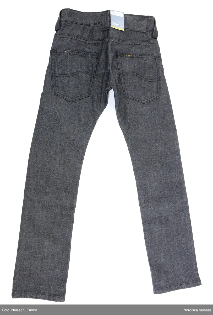 Långbyxor - jeans - i barnstorlek - storlek 9. av märket Lee. Svart bomull (98%) och Elastan (2%), med tre framfickor och två bakfickor, fem söljor för skärp. Framfickorna förstärkta med nitförband. 

Inköpt i nyskick med bibehållen prislapp i midjelinningen (baktill) och med två lappar med information om plagget. Bl.a om att färgen kan fälla samt att det är "Lee Perry Boys Slim & Narrow"

Föremålet inköpt för att rekonstruera julklappsönskemål från Felix Emtefalls, Äppelviken, Stockholm, född 1997. Inköpt av Nordiska museet för 600 kr 2008. Ingår i projektet "Barn tar plats". Se dokumentation i arkivet D455.
/Ulf Hamilton 2008-05-26