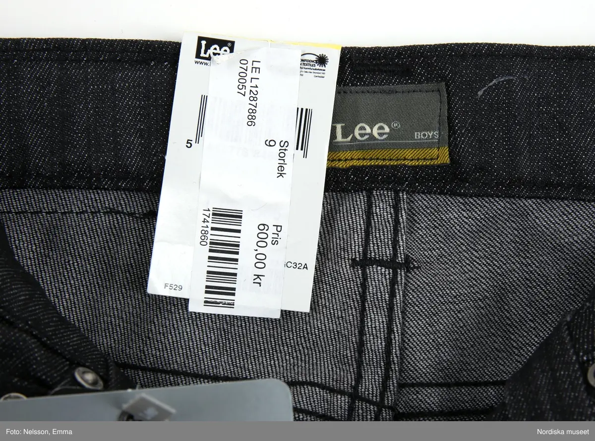 Långbyxor - jeans - i barnstorlek - storlek 9. av märket Lee. Svart bomull (98%) och Elastan (2%), med tre framfickor och två bakfickor, fem söljor för skärp. Framfickorna förstärkta med nitförband. 

Inköpt i nyskick med bibehållen prislapp i midjelinningen (baktill) och med två lappar med information om plagget. Bl.a om att färgen kan fälla samt att det är "Lee Perry Boys Slim & Narrow"

Föremålet inköpt för att rekonstruera julklappsönskemål från Felix Emtefalls, Äppelviken, Stockholm, född 1997. Inköpt av Nordiska museet för 600 kr 2008. Ingår i projektet "Barn tar plats". Se dokumentation i arkivet D455.
/Ulf Hamilton 2008-05-26