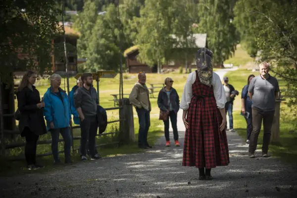 Dame i bunad som holder omvising for ei gruppe