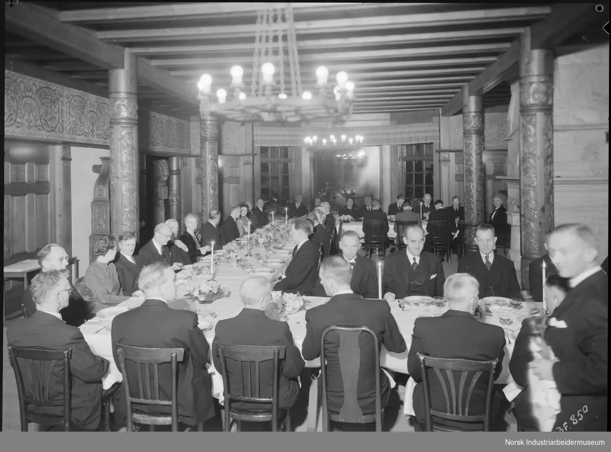 Middag for 40 og 25 års jubilanter 1945 på Adminiet. Mennesker sitter rundt dekket bord.