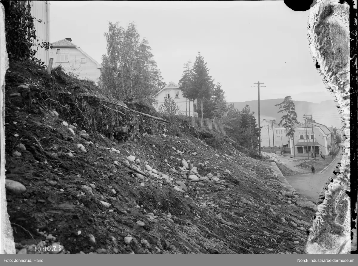 Skråning under rekke med hus. Teater synlig i bakgrunnen.