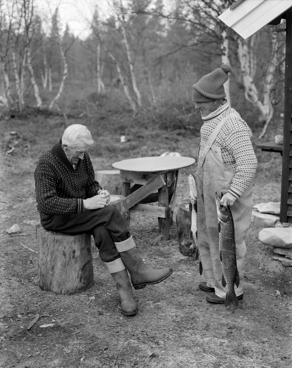 Jo Bakken og Joseph Bakken fra Tufsingdalen i Os kommune i Nord-Østerdalen, fotografert på land under gjeddefisket i Tufsingdeltaet våren 1975.  Jo satt på en hoggestabbe med noe som kan minne om ei vidjespenning i hendene da fotografiet ble tatt. Joseph sto ved sida av ham med ei nyfanget gjedde i hver hand. Begge var kledd i islendere (strikkegensere med spettenmønster). Jo hadde vadmeksbukser på seg. Det hadde sannsynligvis Joseph også, men han hadde dratt en overall av mer vannavstøtende materiale utenpå, åpenbart for å skjerme klærne sine fra det kalde vannet som fulgte med garna. Mens Jo var barhodet hadde Joseph to strikkeluer utenpå hverandre.