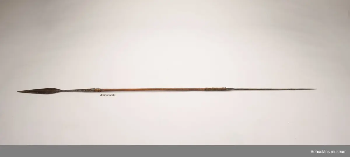 Ur handskrivna katalogen 1957-1958:
Jaktspjut; Afrika
L. 202,5 cm; i ena ändan järnblad, i andra pik av järn; träskaft; delvis lindat m. mässing. Helt.

Lappkatalog: 9