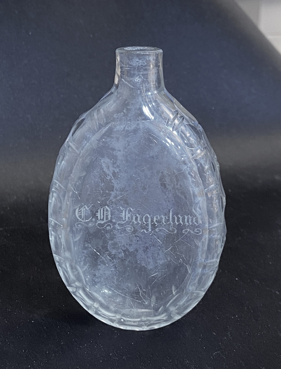 Platt fickplunta med oliv- och skärslipade markeringara längs sidorna. Fram och baksidan är facettslipade, framsidan dessutom försedd med gravyr: "C.A. Fagerlund" (d.v.s. Carl Albert Fagerlund).