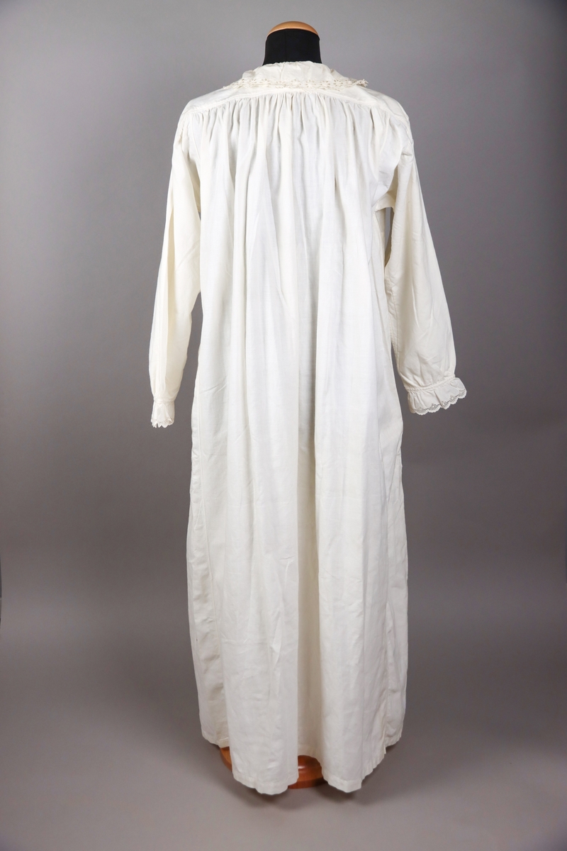 Nattsärk av vit bomull med brodyr. Långa ärmar. Ryggstyckets vidd rynkad mot axelpartiet på ryggen. Djupt ringad på framsidan. Ringningen kantad med bred broderad spets. Dekor av knypplade spetsband som infällts i framstycket över bröstet.