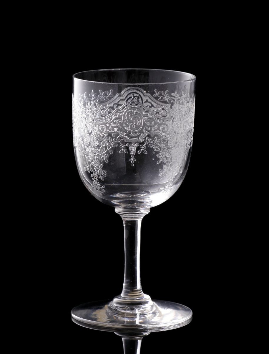 Starkvinsglas med pantograferad dekor i rokokostil.
Liten rund etikett under foten: "Baccarat France" samt teckning av vinglas, karaff och dricksglas.