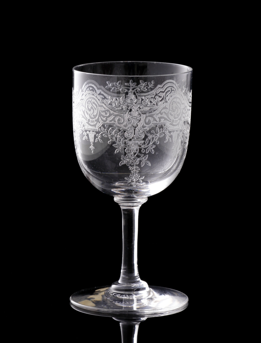 Starkvinsglas med pantograferad dekor i rokokostil.
Liten rund etikett under foten: "Baccarat France" samt teckning av vinglas, karaff och dricksglas.