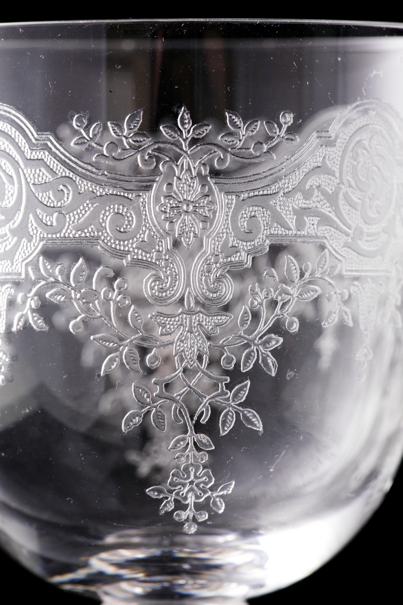 Starkvinsglas med pantograferad dekor i rokokostil.
Liten rund etikett under foten: "Baccarat France" samt teckning av vinglas, karaff och dricksglas.
