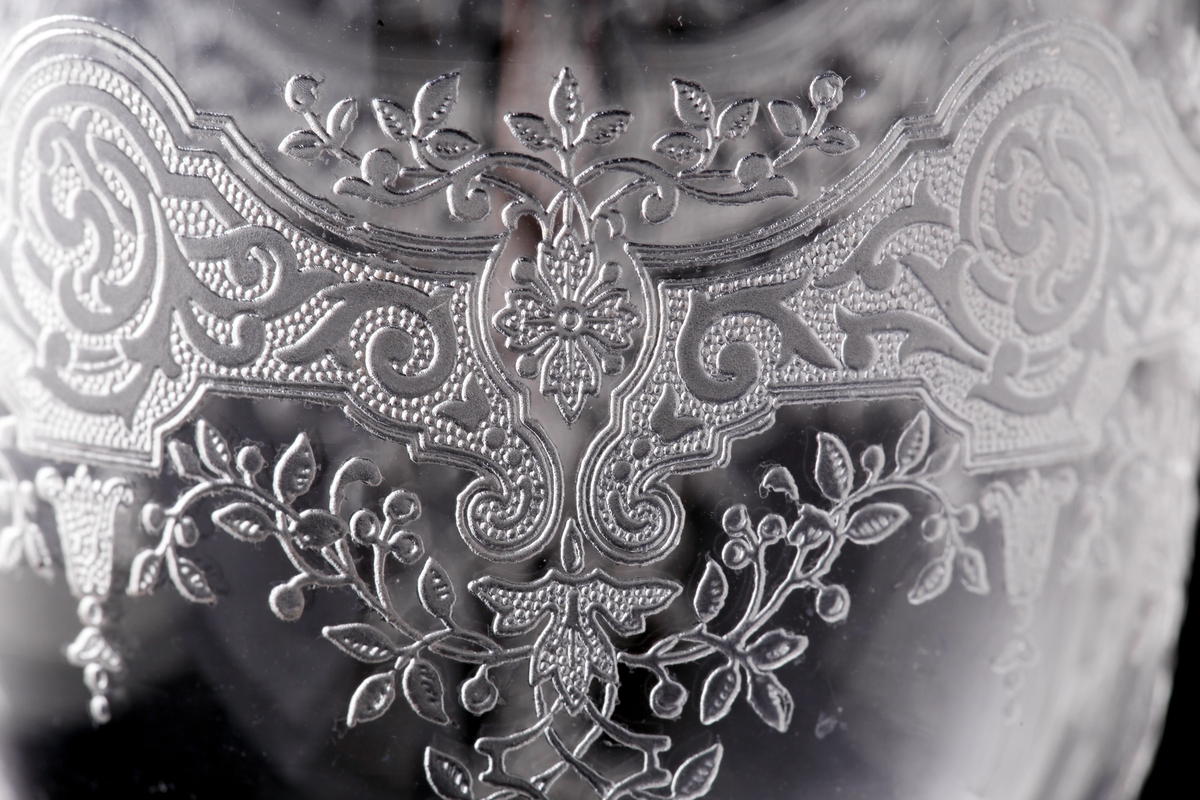 Starkvinsglas med pantograferad dekor i rokokostil.
Liten rund etikett under foten: "Baccarat France" samt teckning av vinglas, karaff och dricksglas.