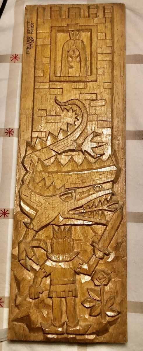 Glasrelief i grönt glas. Formgiven av John Käll.
Rektangulär tavla föreställande St. Göran och draken. Prinsessa i torn, drake, prins med svärd. Gjuten i form. Ytan med oregelbunden struktur. 
Inskrivet i huvudkatalog: Tidigast 1988.