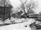 Motiv från kvarnfallet i Tannefors en vinterdag år 1900. Till vänster reser sig Erikssons valskvarn i tre våningar. På fallets högra sida ligger närmast en byggnad med oklar funktion. Bortom gångbron ligger Hospitalskvarnen och därefter Bolagskvarnen med tegelfasad.