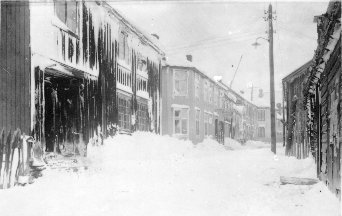 Gateparti fra Tufta på Røros etter snøstorm. Øvre del av Peder Hiortgata mot Nilsen-hjørnet med Hartz-gården til venstre. Grønngården med Dovres ekspedisjon sentralt i bildet.