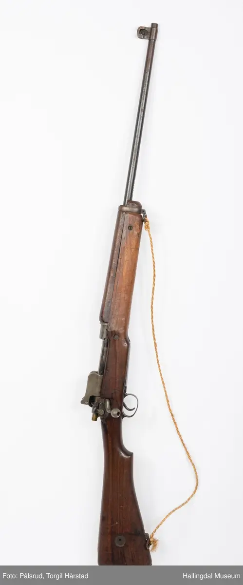 Engelsk Lee-Enfield rifle. Brukt under andre verdenskrig i Norge. 
Framstokken er noe avkappet - mulig i forbindelse med ombygging til jaktvåpen. 
Kaliber: .303 British. 
Geværet har et surret hampetau til reim - ikke original.